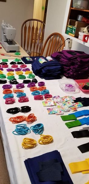Rows of colorful elastic hair ties lined up on a table with a white covering